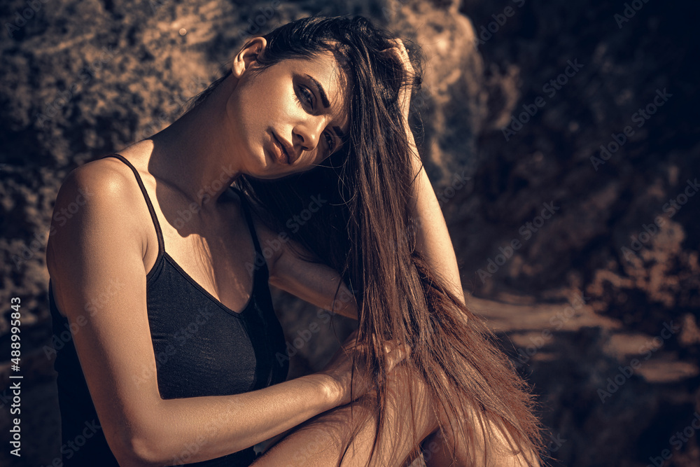 Girl in a black dress posing on a background of sand rocks. Portrait Girl in a black dress posing on a background of sand rocks. Portrait