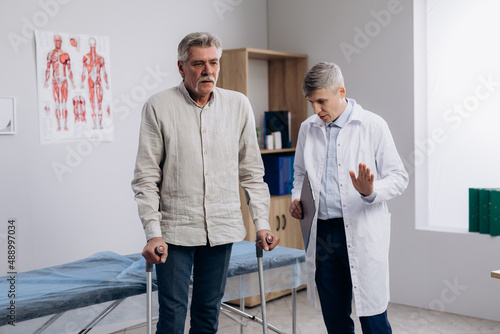 Tablou pe pânză senior man recovering after surgery, using walking sticks to make steps