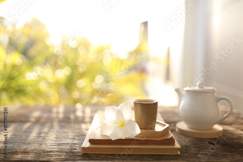 Tea cup and white tea pot and notebook with plumeria flower