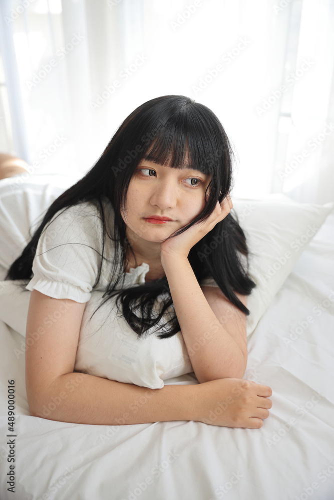 Beautiful young Asian woman sleeping on bed relaxing in the morning light with white room Beautiful young Asian woman sleeping on bed relaxing in the morning light with white room