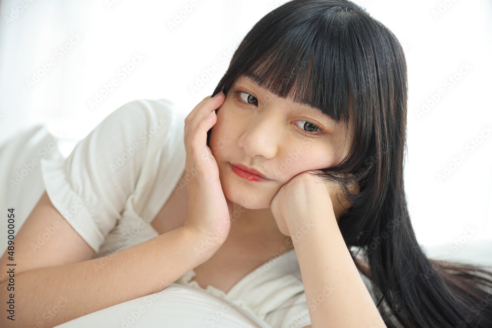 Beautiful young Asian woman sleeping on bed relaxing in the morning light with white room