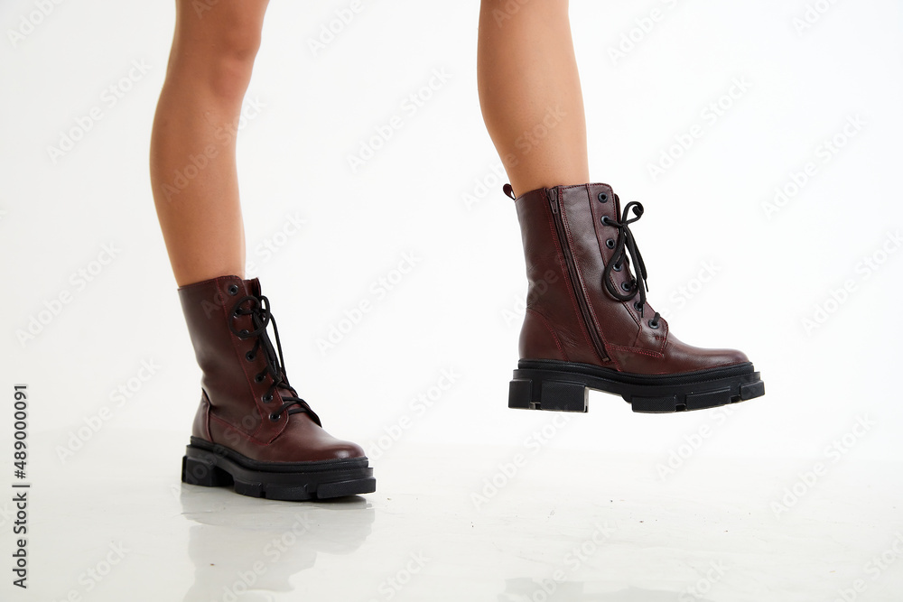 Female winter, autumn or spring brown leather shoes on leg of woman in studio on white background. Fashionable modern photography and photoshoot for a store, catalog, magazine or online Female winter, autumn or spring brown leather shoes on leg of woman in studio on white background. Fashionable modern photography and photoshoot for a store, catalog, magazine or online