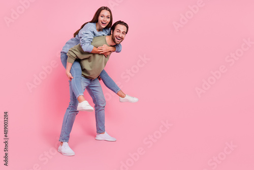 Full body profile portrait of two carefree people carry piggyback enjoy free time isolated on pink color background