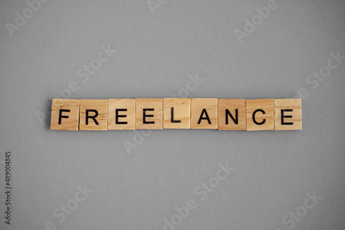 Word freelance. Wooden blocks with lettering on top of gray background. Human Resource Management and Recruitment and Hiring concept. Top view above flat lay.