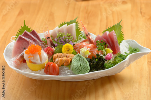 Fresh Japanese food mixed Sashimi Moriawase platter (raw seafood) with ice, fish slice a dish isolated on wooden background top view