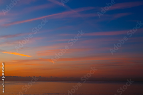 Trazos en el cielo de color naranja al amanecer con fondo azul