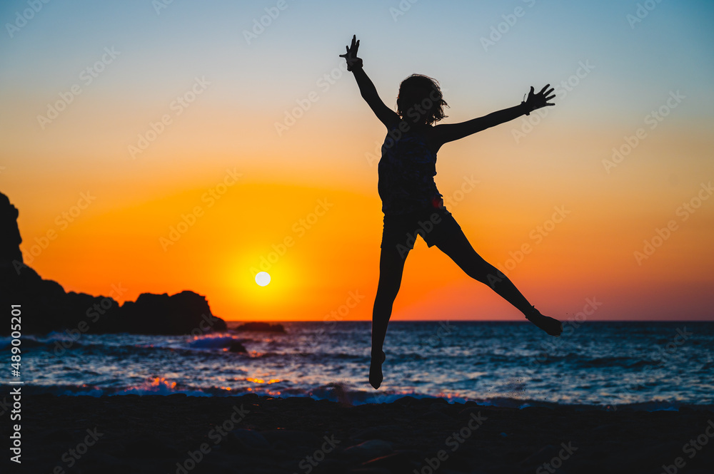 Silhouette of a child jumping in sunset on a beach.