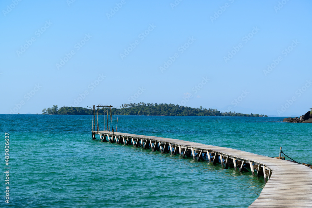 Arched wooden bridge that extends into the sea to serve as a pier, Klong Mard, Koh Kood, Trat, Thailand.