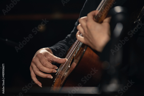 Closeup photo of male guitarist playing an electric acoustic ten-string midi guitar by fingers