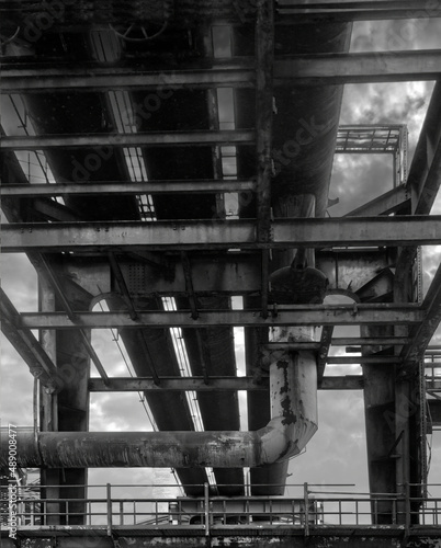 Pipe bridge with thick metal pipes, abstract view from below, black and white