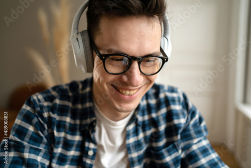 Gamer adult male in wireless headphones and glasses, close portrait happy playing a game