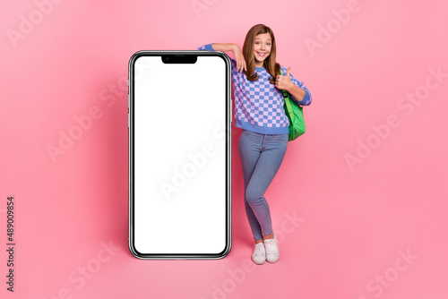 Full size photo of funky girl thumb up recommend cellphone offer wear backpack isolated pink color background