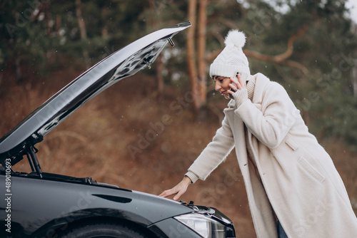 Young woman calling on the phone after her car brokedown in winter season photo