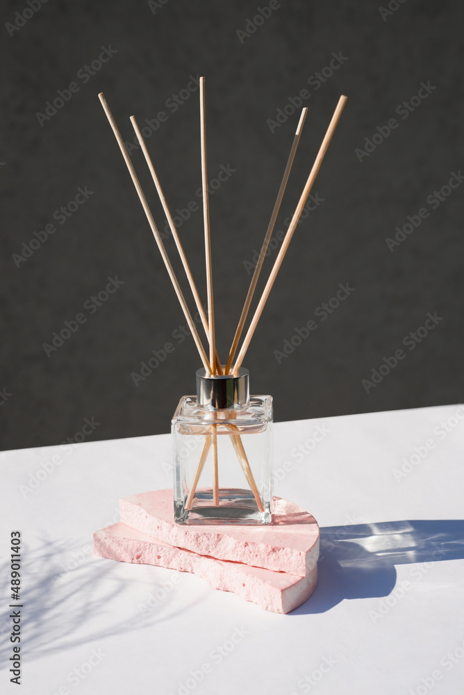Transparent bottle of aroma diffuser on a light grey background. Eau de ...