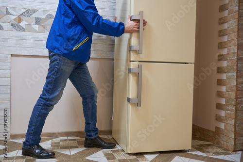 refrigerator delivery,buy a new refrigerator, a man places a refrigerator in the kitchen