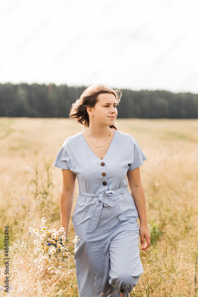 .Beautiful girl with a bouquet of wildflowers on a meadow in sunlight. Summer background.
