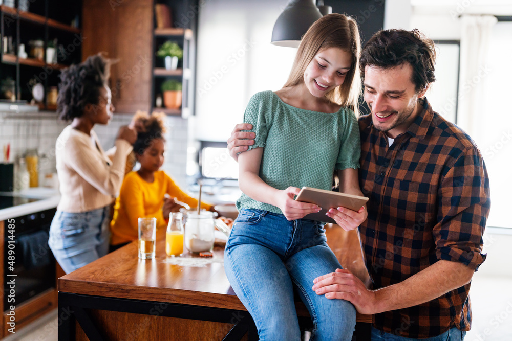 Portrait of happy multiethnic family having fun in kitchen and using digital tablet while cooking.