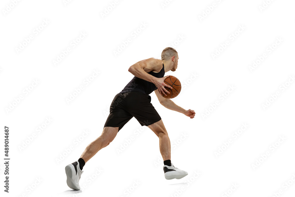 Young muscled man, basketball player practicing with ball isolated on white studio background. Sport, motion, activity concepts.