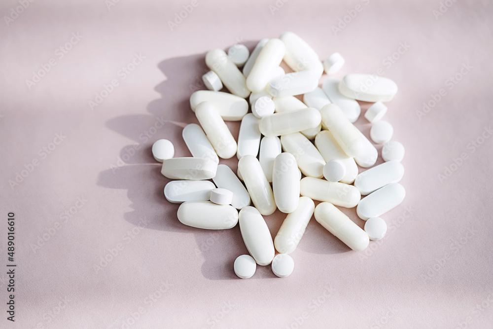 Stack of different pills, heap vitamin capsules on pastel pink background. Dietary supplement supports for health. Stack of different pills, heap vitamin capsules on pastel pink background. Dietary supplement supports for health.