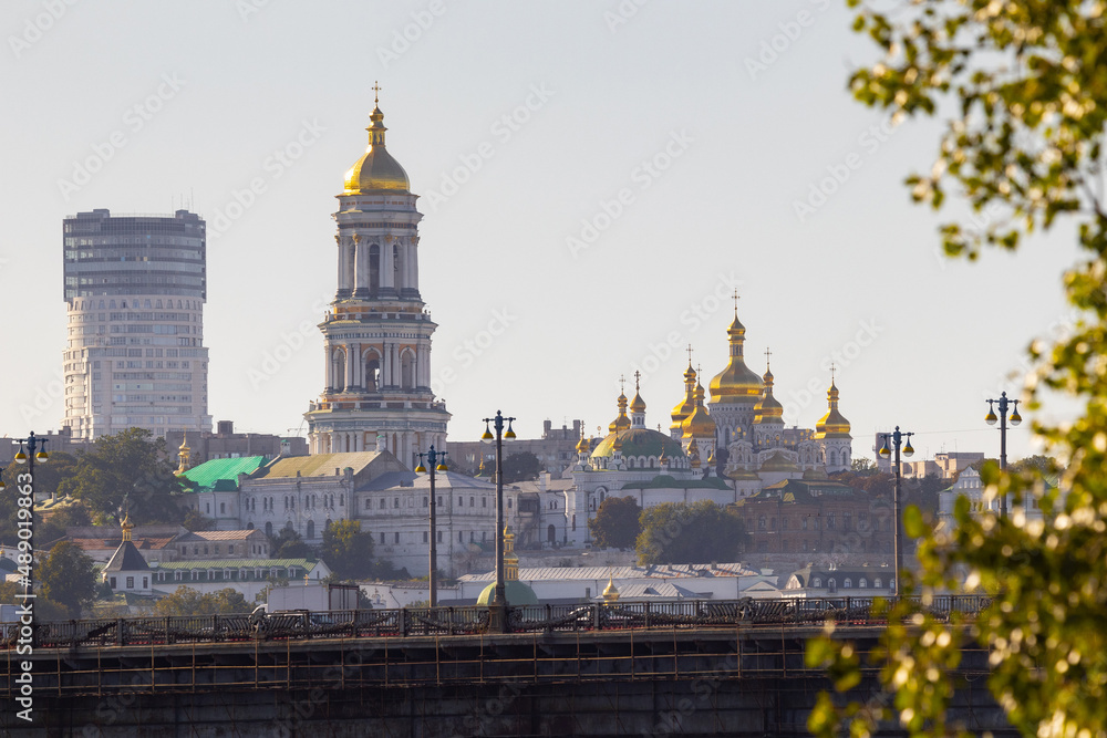 Naklejka premium Bright evening cityscape of the big city on the hill over wide river Dnipro in awesome bright sunset in Kyiv, Ukraine. View at Kyiv-Pechersk Lavra National Reserve.
