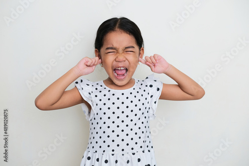 Asian kid screaming loud and closed her ears with finger photo