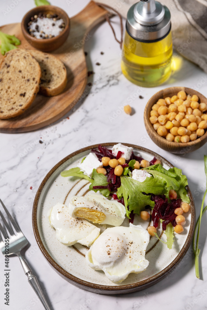 Easter breakfast or brunch. Poached egg and beet salad with spinach, cheese feta, chickpeas on a marble tabletop. Easter breakfast or brunch. Poached egg and beet salad with spinach, cheese feta, chickpeas on a marble tabletop.