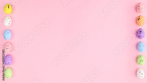 Easter pastel pink background with vibrant eggs on left and right side. Copy space creative layout. © Long Frame