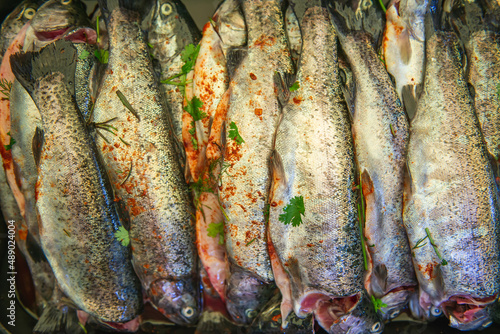 fresh and marinated fish ready for grilling, decorated with herbs and vegetables