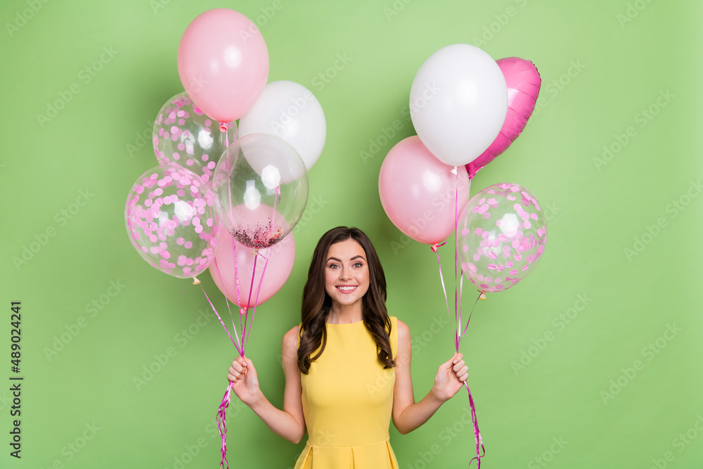 Portrait of attractive cheerful girly wavy-haired girl holding air balls occasion isolated over bright green color background