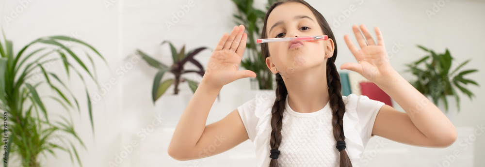 Smart little schoolgirl with pen and books writing a test in a classroom. Child in an elementary school. Education and learning for kids. Smart little schoolgirl with pen and books writing a test in a classroom. Child in an elementary school. Education and learning for kids.