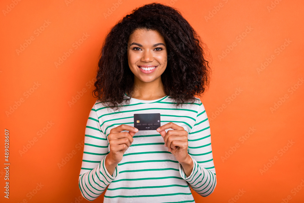 Photo of cute millennial volume hairdo lady hold card wear shirt isolated on orange color background Photo of cute millennial volume hairdo lady hold card wear shirt isolated on orange color background