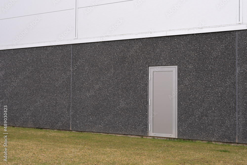 Εκτύπωση καμβά a gray aluminum door on a dark gray concrete warehouse with a lawn in the foregr