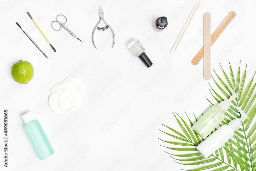 Nail care. Flat lay manicure or pedicure tools on white table with green leaves. High quality photo