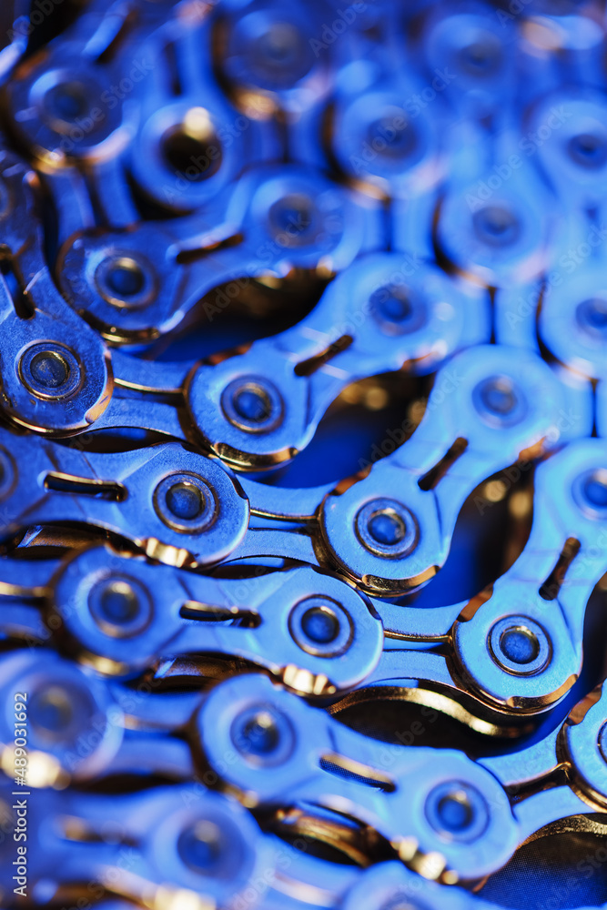 The texture of a shiny bicycle chain with a bluish-purple backlight The texture of a shiny bicycle chain with a bluish-purple backlight