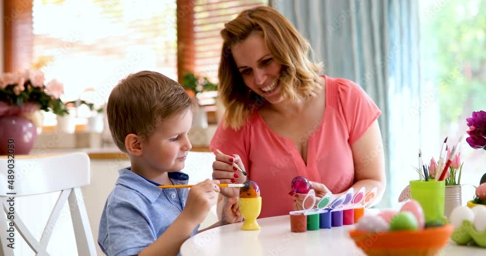 Happy mother and son paint Easter eggs at home together. People holiday happiness concept Happy mother and son paint Easter eggs at home together. People holiday happiness concept