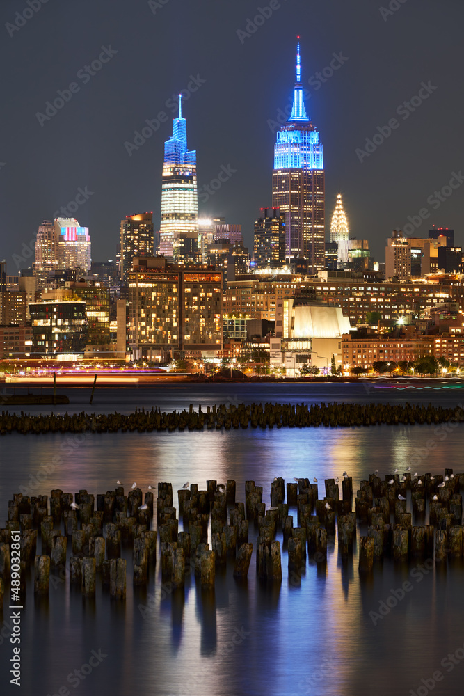 Obraz premium Historic New York skyscrapers illuminated at night from across the Hudson River. Cityscape of West Village and Midtown Manhattan