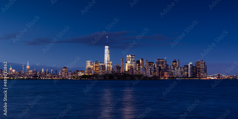 New York City Lower Manhattan cityscape in evening. View of  Financial District skyscrapers with World Trade Center, Midtown West and Ellis Island
