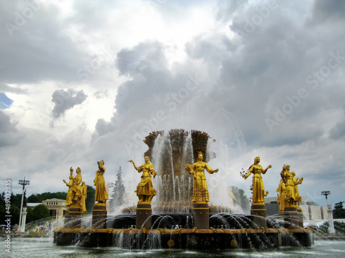 Fountain with sculptures of golden women. Slightly blurred background.