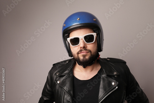Bearded biker man posing in leather jacket and blue motorcycle helmet. © face_reader_img