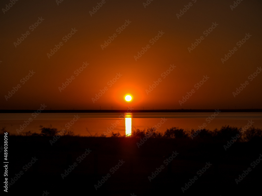 Yellow Sun Reflecting on the Lake Against an Orange Sky for a Dramatic Sunset