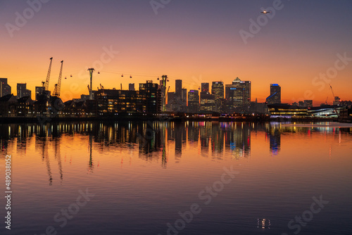 Sunset over the London skyline with orange sky reflecting in the water. © Robert