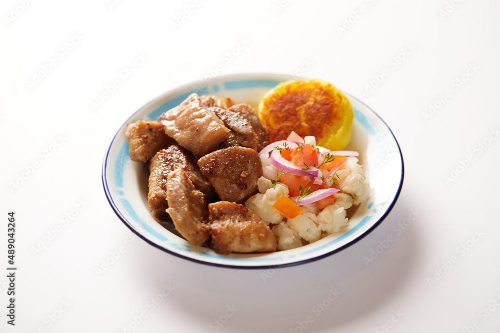Homemade fritada a typical ecuadorian dish that consists on braised pork. It’s served on a traditional plate with a white background Homemade fritada a typical ecuadorian dish that consists on braised pork. It’s served on a traditional plate with a white background