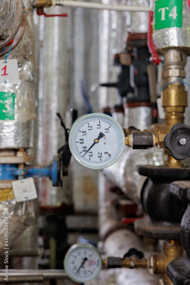 Closeup of manometer, pipes and faucet valves of heating system in a boiler room Closeup of manometer, pipes and faucet valves of heating system in a boiler room