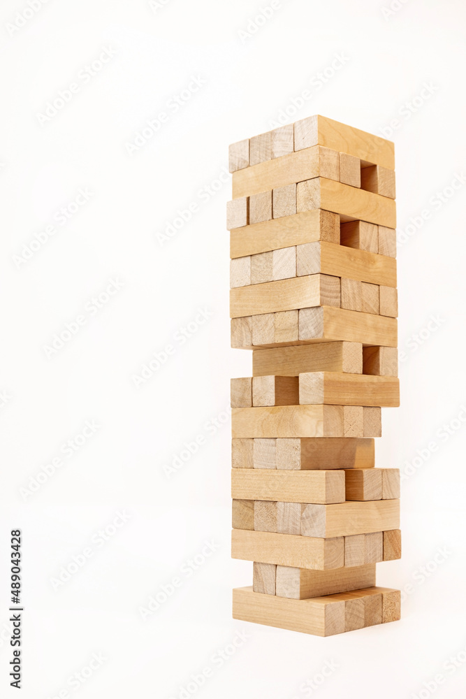 A game of logic and the ability to think. Jenga tower with wooden blocks on a white background. The tower is half dismantled. A game of logic and the ability to think. Jenga tower with wooden blocks on a white background. The tower is half dismantled.