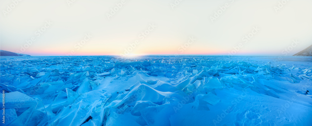 Beautiful winter landscape of frozen Lake Baikal at sunrise - Snowy ice hummocks with transparent blue piles of ice - Baikal Lake, Siberia