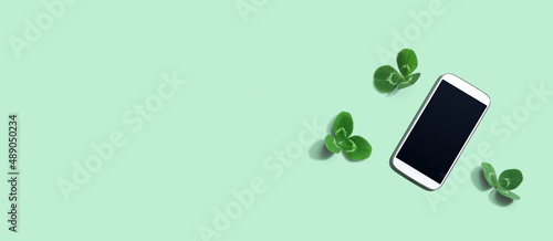 White smartphone with shamrock leaves - flat lay