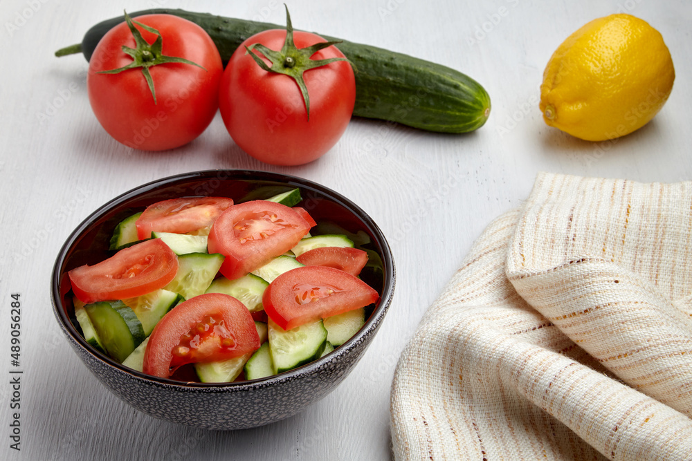 Fresh tomato and cucumber salad in dark bowl and kitchen napkin Fresh tomato and cucumber salad in dark bowl and kitchen napkin