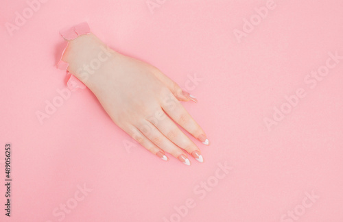 female hands with beautiful long nails with  manicure  on pink paper  background