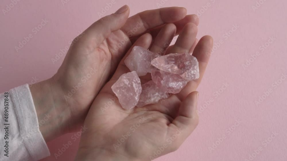 Pouring pink rose quartz crystals from one palm of hand into the other, slow motion Pouring pink rose quartz crystals from one palm of hand into the other, slow motion