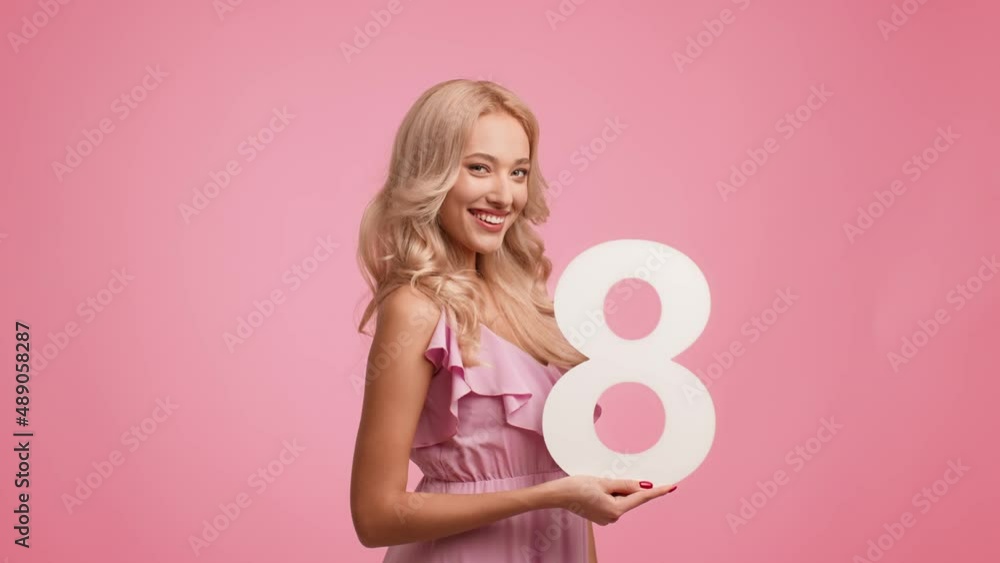 Lady Holding Number Eight Winking Eye, Celebrating Holiday, Pink Background Lady Holding Number Eight Winking Eye, Celebrating Holiday, Pink Background